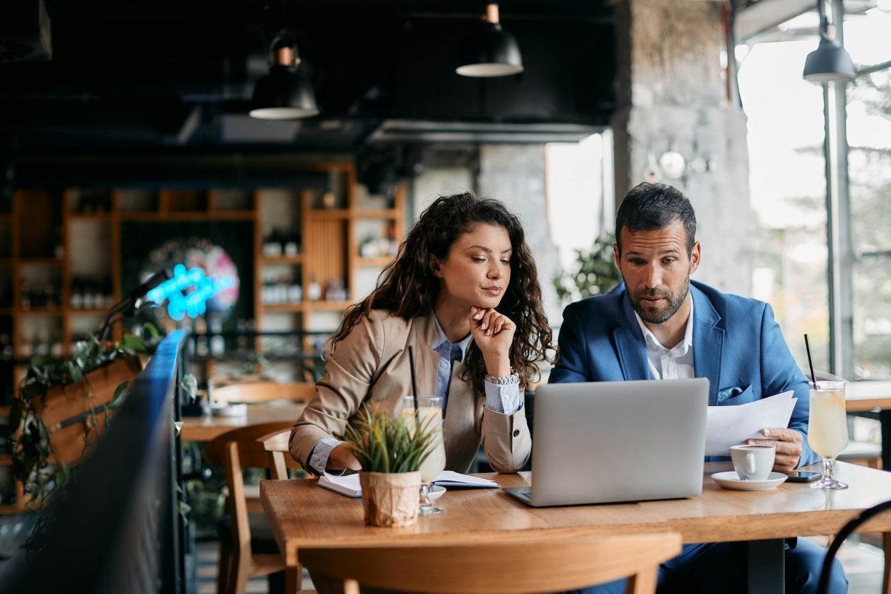 business-colleagues-using-laptop-and-analyzing-documents-on-a-meeting-in-cafe-.jpg